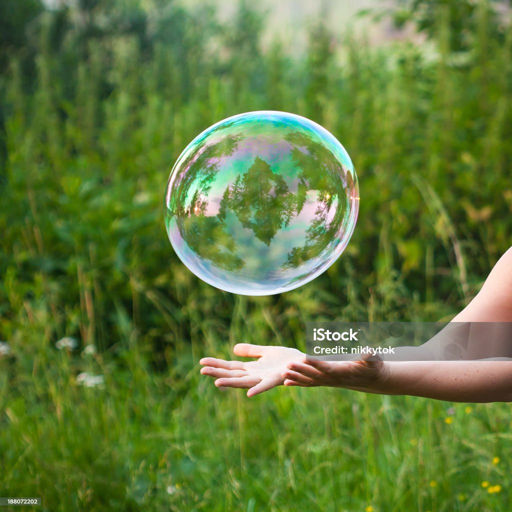 hand catching a soap bubble hand catching a soap bubble and green grass as the background Soap Sud Stock Photo