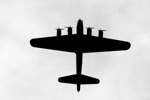 A backlit B-17G bomber passes overhead.