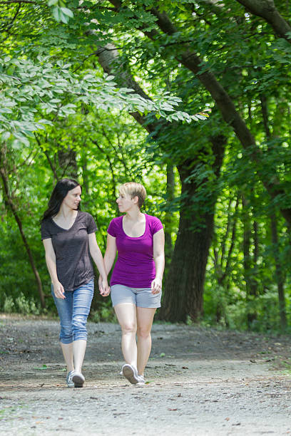istock Two women holding hands and walking in park, vertical 188079905