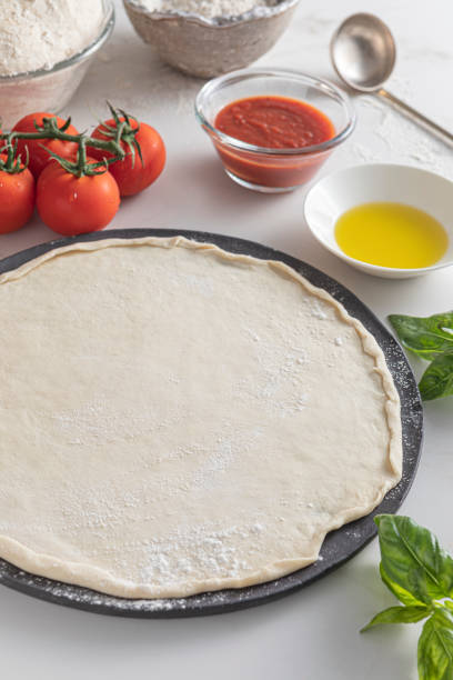 istock Raw dough for pizza with ingredient: tomato sauce, dough, mozzarella, tomatoes, basil, olive oil, spices served on rustic marble table 1880827953