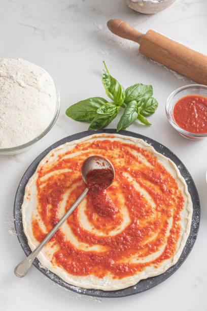 istock Spreading tomato sauce on the pizza raw dough 1880833909