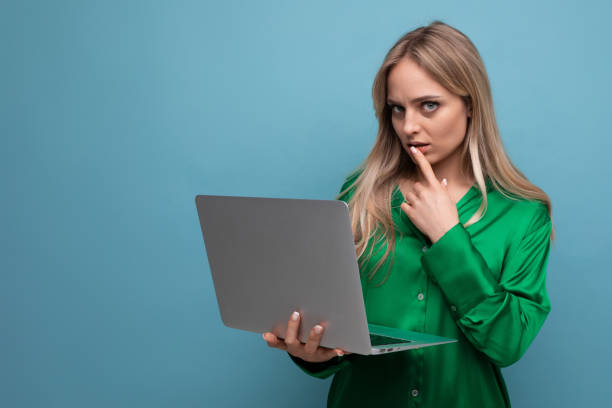 istock business lady freelancer thinking about work holding a laptop in her hands on a blue bright background 1880841896