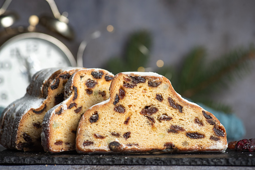 Christmas stollen - traditional German bread on a grey background. Festive dessert made of dough, nuts and raisins, sprinkled with powdered sugar