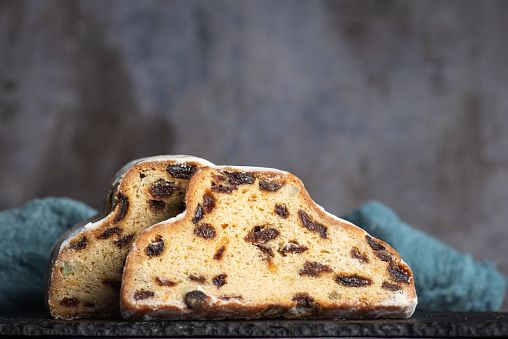 Christmas stollen - traditional German bread on a grey background. Festive dessert made of dough, nuts and raisins, sprinkled with powdered sugar. Copy space