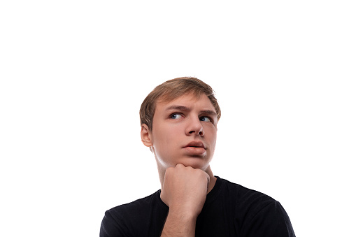 Portrait of a pensive blond teenager guy on a white background.