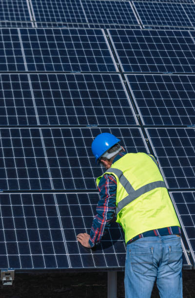 istock A solar panel installer, equipped with a drill, is in the process of installing solar panels on a solar energy power station on a sunny day 1880857340