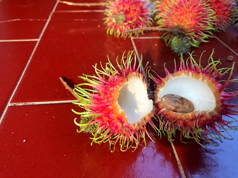 Rambutan bark is cut in half on glass dish and ready to eat.