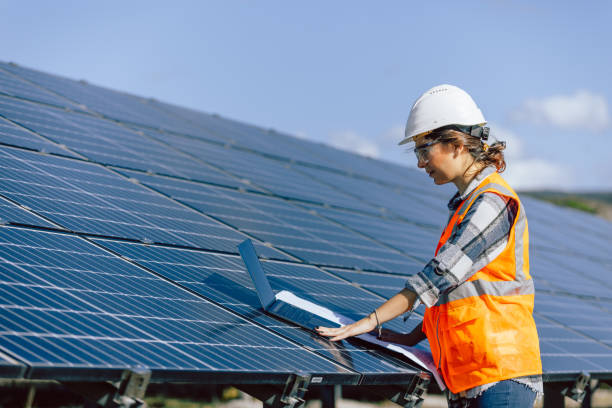 solar power sentinel: porträt einer jungen elektroingenieurin, die mit laptop und bauplan in einer photovoltaik-solaranlage für spitzenleistung sorgt - solar panel solar power station sun solar energy stock-fotos und bilder