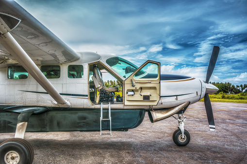 Small airplane parked on a runway with door open