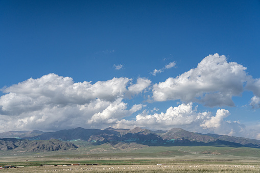 Clear blue sky and white clouds, the mountainous terrain on the desolate plateau