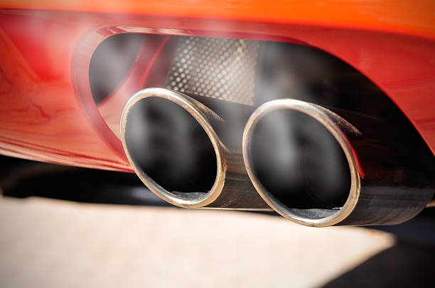 Smoky Exhaust Pipe Close up of a red car dual exhaust pipe with smoke around it exhaust pipe photos stock pictures, royalty-free photos & images