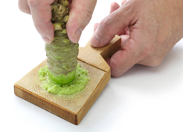 grating fresh wasabi by shark skin grater grating fresh wasabi by shark skin grater, japanese condiment wasabi sauce stock pictures, royalty-free photos & images