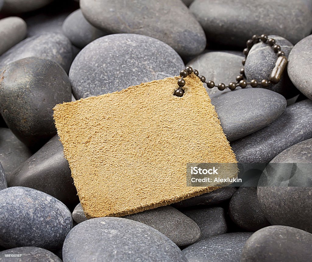 Yellow leather label Yellow leather label with a chain on the pebbles Backgrounds Stock Photo