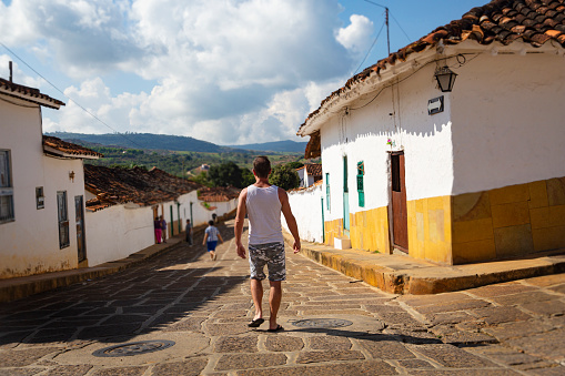 A view of a male tourist from behind walking down a street in the pretty and popular tourist town of Barichara. Barichara is a town in northern Colombia known for its cobbled streets and colonial architecture and a very popular tourist destination.