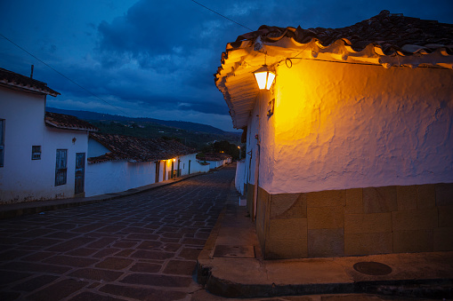A street just as night is falling, with a lamp illuminating the corner - in the lovely colonial town of Barichara, which has white washed houses, cobble stoned streets and red tiled roofs. The town was declared a national monument in 1978.