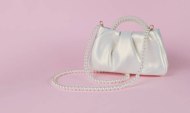 istock Stylish white women's bag trimmed with pearls on a pink background. 1881105603