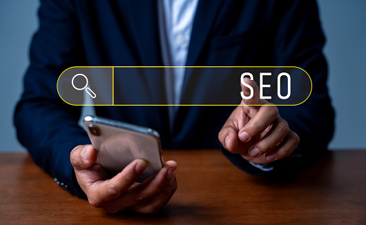 Search engine optimization marketing ranking. Working on smartphone with the icon of online search engine, abbreviation SEO and SEO symbol. Digital marketing strategy of promoting traffic to website.