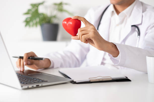 istock Doctor holding heart shape to camera in office 1881119489