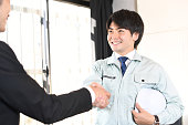 A businessman in work clothes is shaking hands with a male customer in a suit