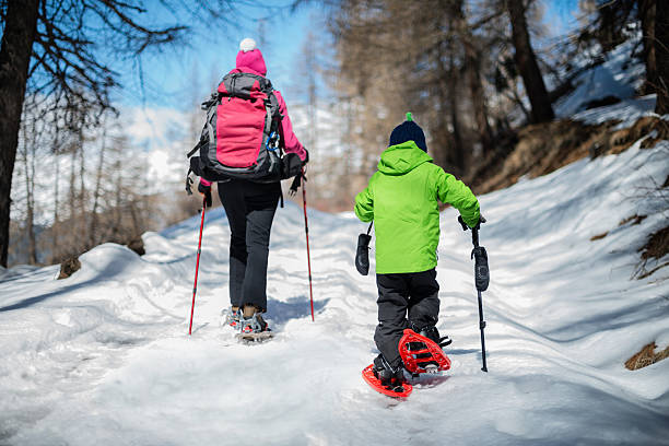 мать и сын на прогулку в снегоступах - snowshoeing snowshoe child winter стоковые фото и изображения
