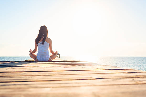 istock young woman doing yoga on pier 188126531