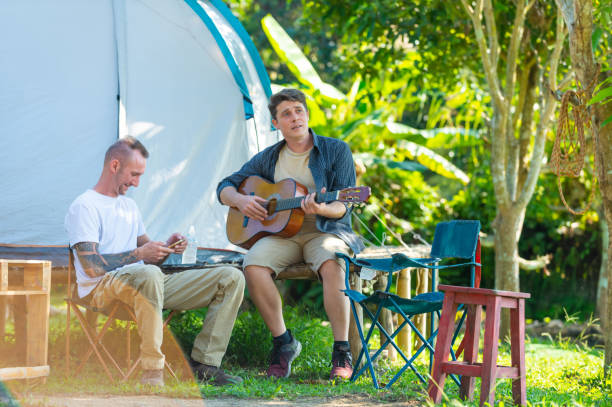 istock Caucasian man friends playing guitar at camp. 1881340699