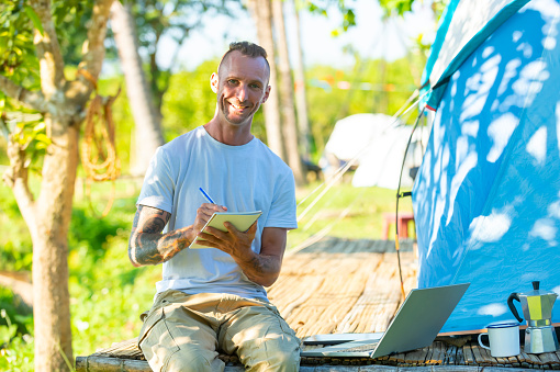Caucasian man using laptop computer working corporate business video conference. People remote work with wireless technology outside office. Handsome guy relax and enjoy outdoor lifestyle travel nature and camping on summer holiday vacation.