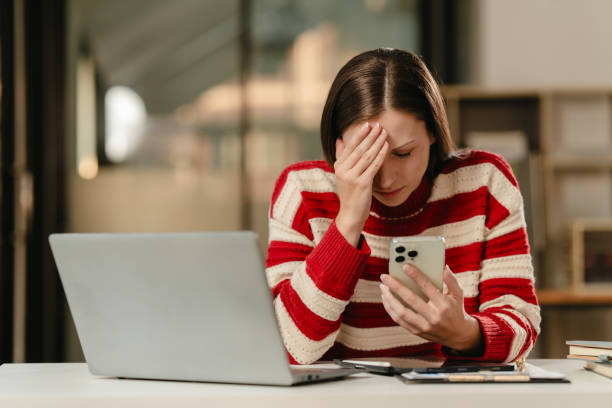 istock stressed Caucasian university student with a hand on her forehead, looking at a laptop, possibly overwhelmed with work. 1881372784