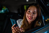 Asian businesswoman commuting from office in Taxi backseat with mobile phone on road