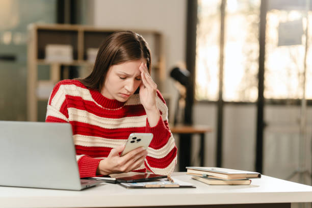 istock stressed Caucasian university student with a hand on her forehead, looking at a laptop, possibly overwhelmed with work. 1881372792