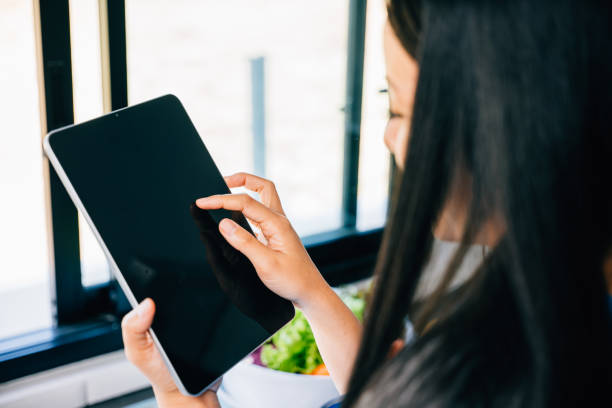 istock Asian woman joyfully cooks in her sunlit kitchen utilizing a tablet 1881374896