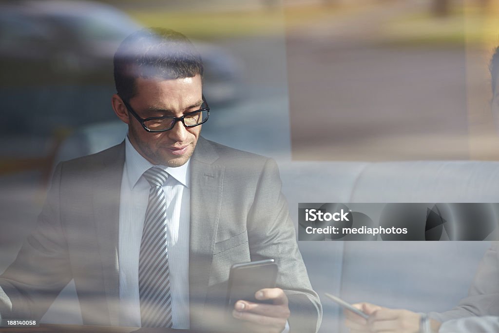 Businessman using smart phone Through window shot of businessman using his smart phone during meeting in cafe 30-39 Years Stock Photo