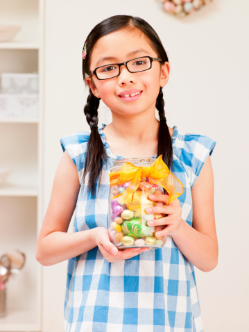 Oriental young girl with a glass jar full of mini easter eggs