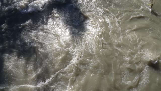 Up and down drone aerial view of the a river swollen after heavy rains. The water flows quickly. Risk of flooding and overflow. General contest of a river flood