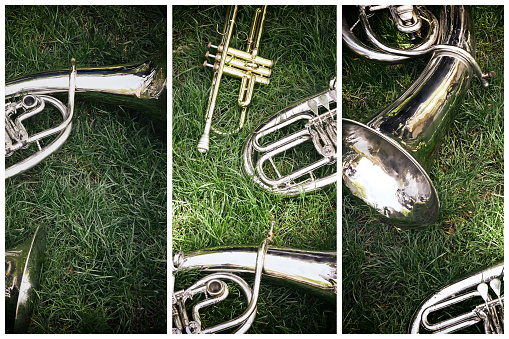 Close-up of a set of old musical instruments of a brass band of a tenor or baritone or trumpet on green grass in a park. Artistic image processing.