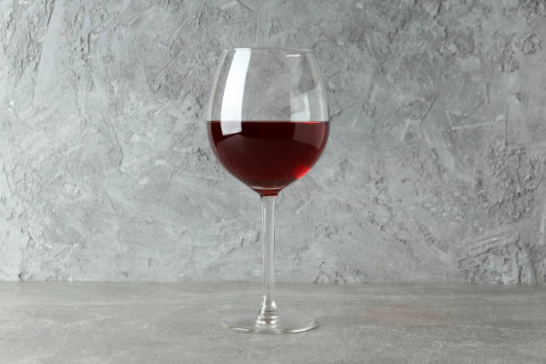 istock Glass of red wine on gray textured table 1881574778