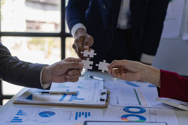 istock Businessman's hands holding a paper jigsaw puzzle and solving puzzles together, solving problems, finding a way out of a difficult situation. Support the concept of teamwork 1881604776