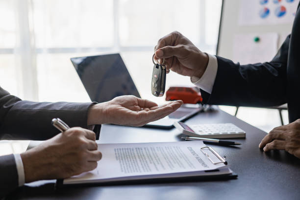 Car dealer hands keys to customer, closing car insurance documents or rental agreement or agreement. Buying or selling a new car, close-up photo stock photo