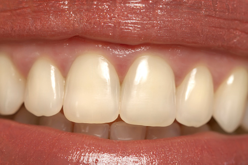 Close-up of a woman's mouth, capturing a confident smile and perfect natural teeth and lips