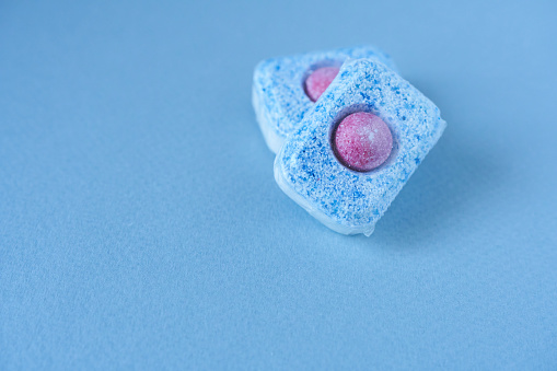 Dishwasher tablets on blue background. Copy space.  Shallow focus.