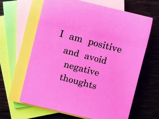 Pink note with message I AM POSITIVE AND AVOID NEGATIVE THOUGHTS, concept of affirmation message or self talk to challenge negative inner voice and boost self esteem