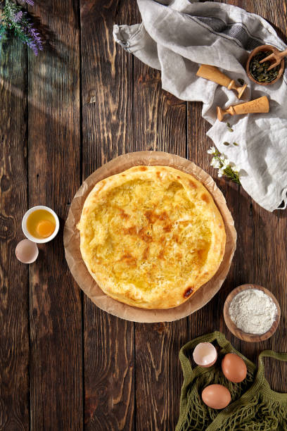 istock Megrelian-style khachapuri on textured wood, with eggs and flour, under natural light, rustic Georgian charm 1881732522