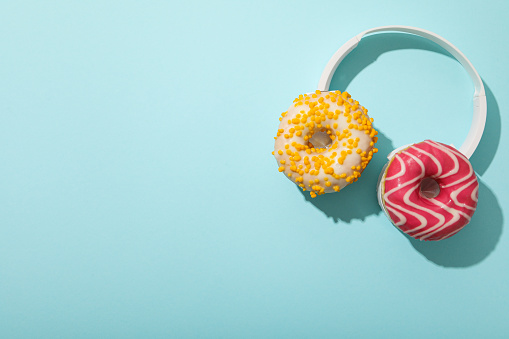 Donuts and headphones on blue background, space for text