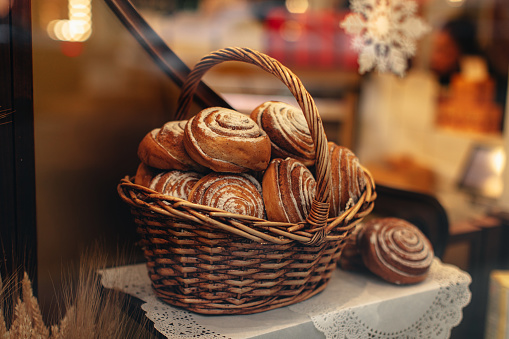 Sweet fresh baked twisted bread buns in a wicker basket. Bakery shop counter