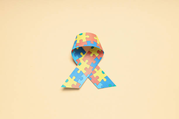 istock Ribbon with multi-colored puzzle pieces on a light background. World autism day concept 1881765587