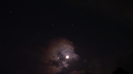 Eerie planets and moon aligned in cloudy sky