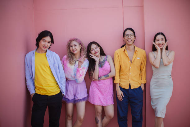Friends smiling directly at the camera against a soft pastel pink background.