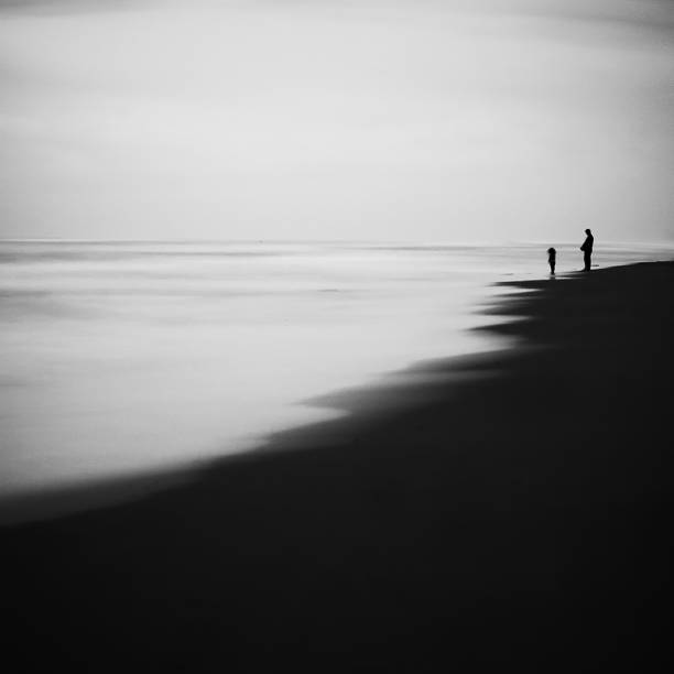 istock two people stand on a beach, watching the waves roll 1881784902
