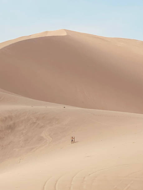 istock Person climbing a dune in a vast desert 1881787003