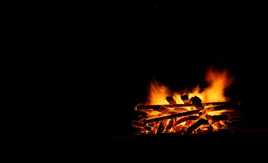 A burning wooden bonfire radiating a warm, orange glow in a dimly lit room.